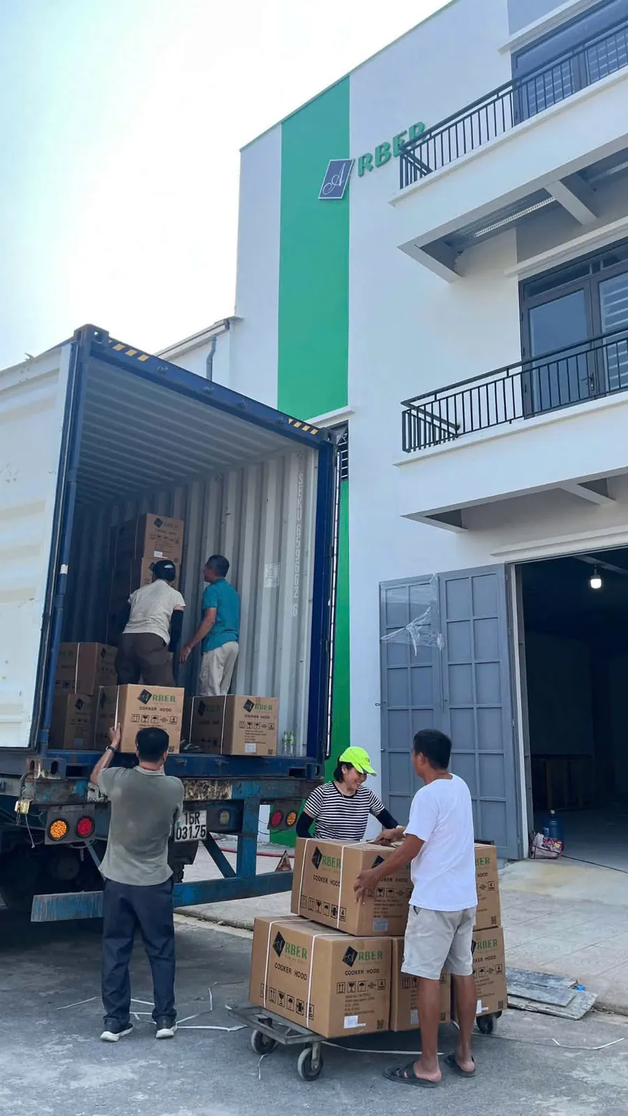 Công nhân dỡ thùng hàng từ container trước tòa nhà ARBER sọc xanh tại Bắc Ninh